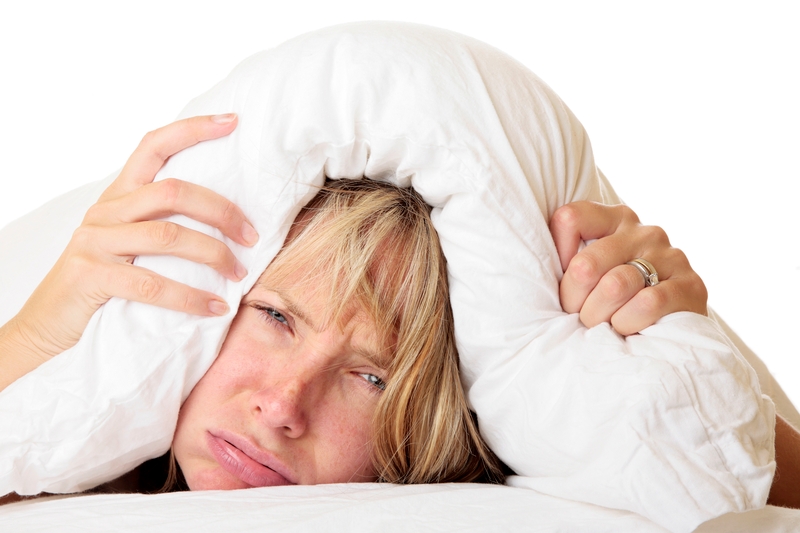 woman with insomnia, woman frustrated by lack of sleep, woman under pillow grimacing, sleep for brain health, important sleep for healthy brain function